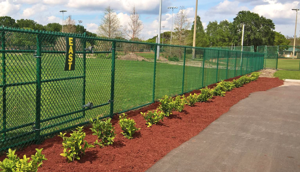 Green chain-link fence along a commercial property.”